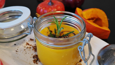 Kürbissuppe im Glas mit Kübissen im Hintergrund